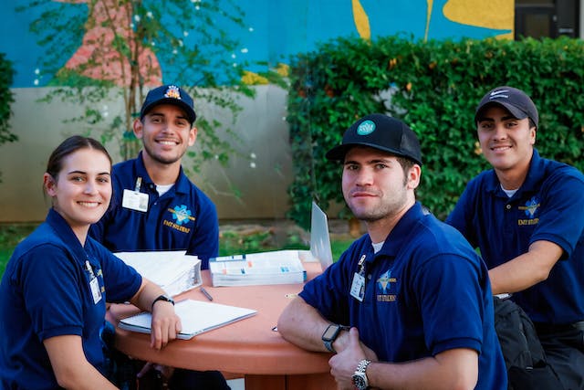 EMT Wearing Blue T shirts and Caps Posing by a Table